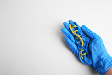 Photo of Scientist holding DNA molecule model made of colorful plasticine on white background, top view. Space for text