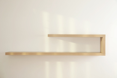 Photo of Empty stylish wooden shelf on light wall