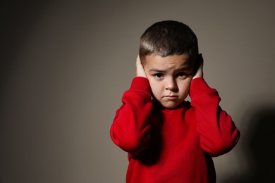 Photo of Scared little boy on beige background, space for text. Domestic violence concept