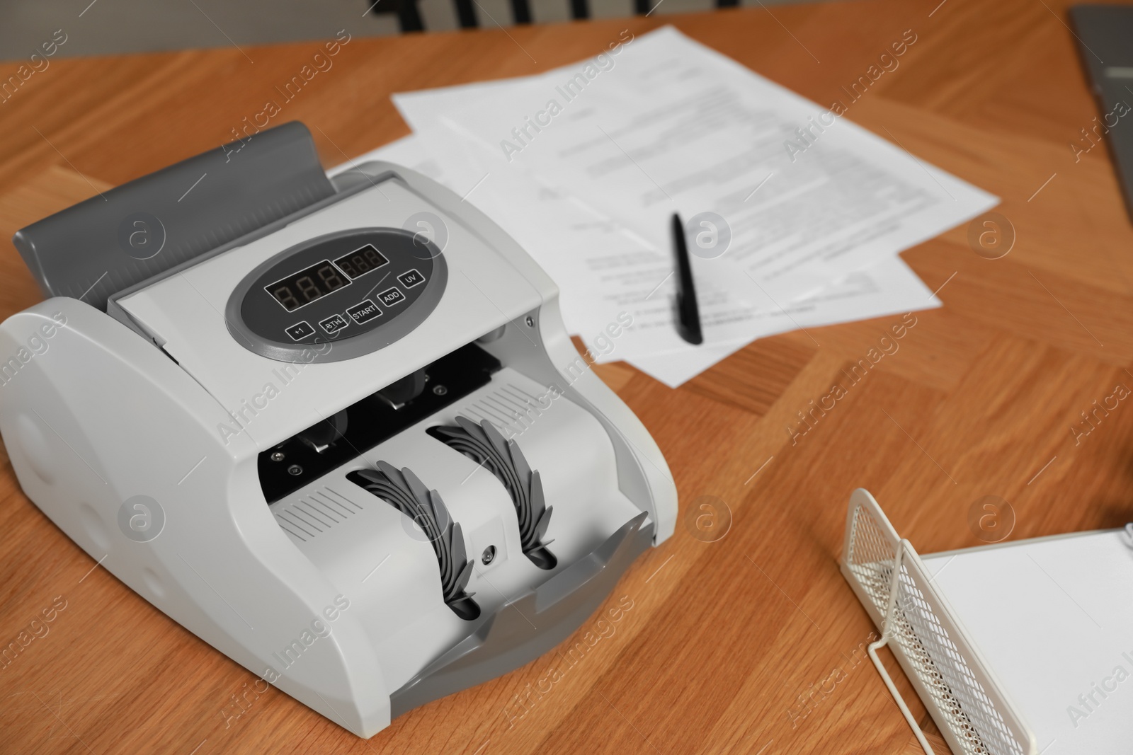 Photo of Modern banknote counter on wooden table, above view