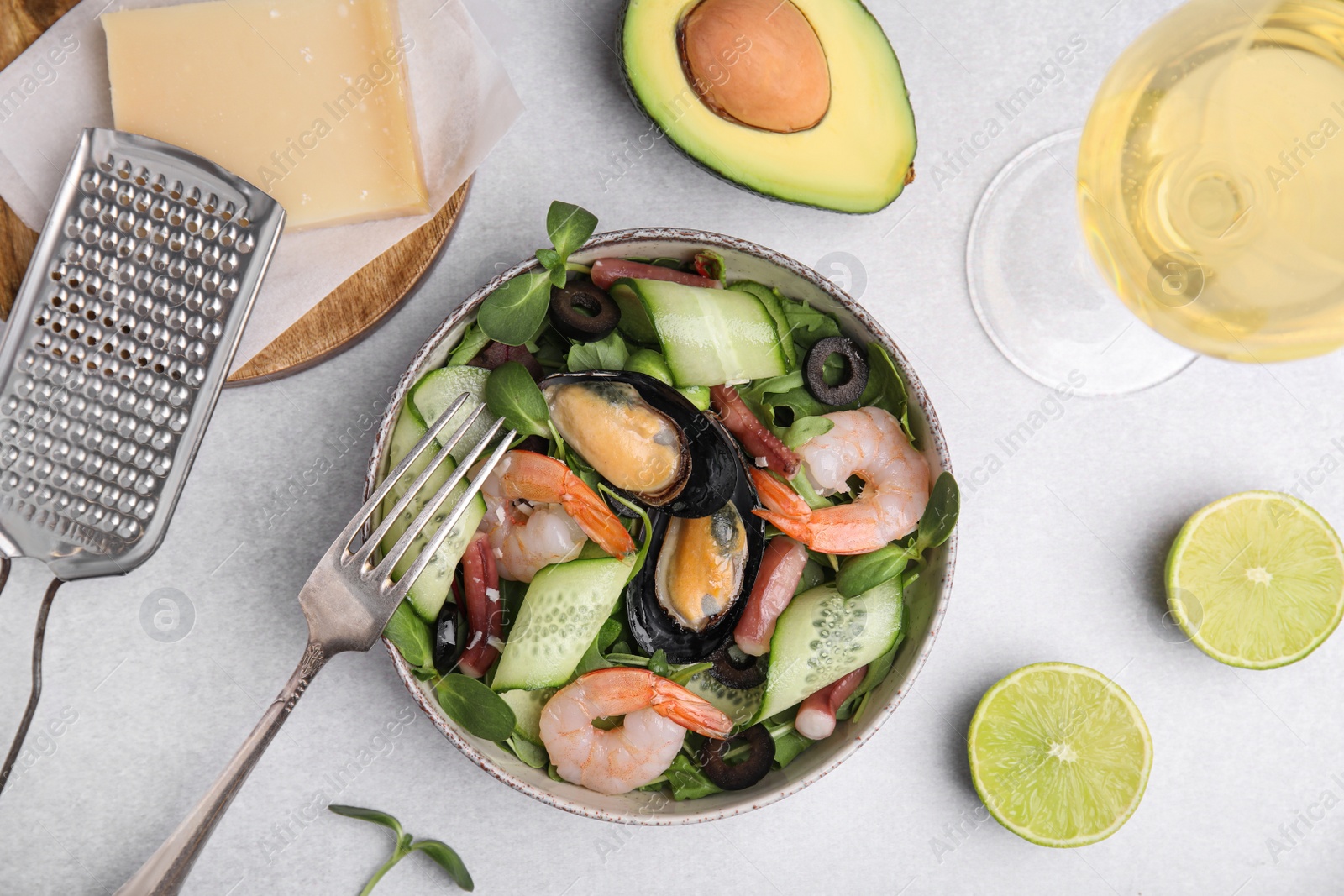 Photo of Bowl of delicious salad with seafood on light grey table, flat lay