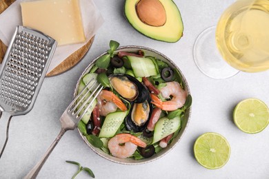 Bowl of delicious salad with seafood on light grey table, flat lay