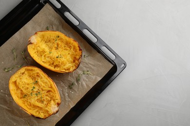 Photo of Baking sheet with halves of cooked spaghetti squash and thyme on light grey table, top view. Space for text