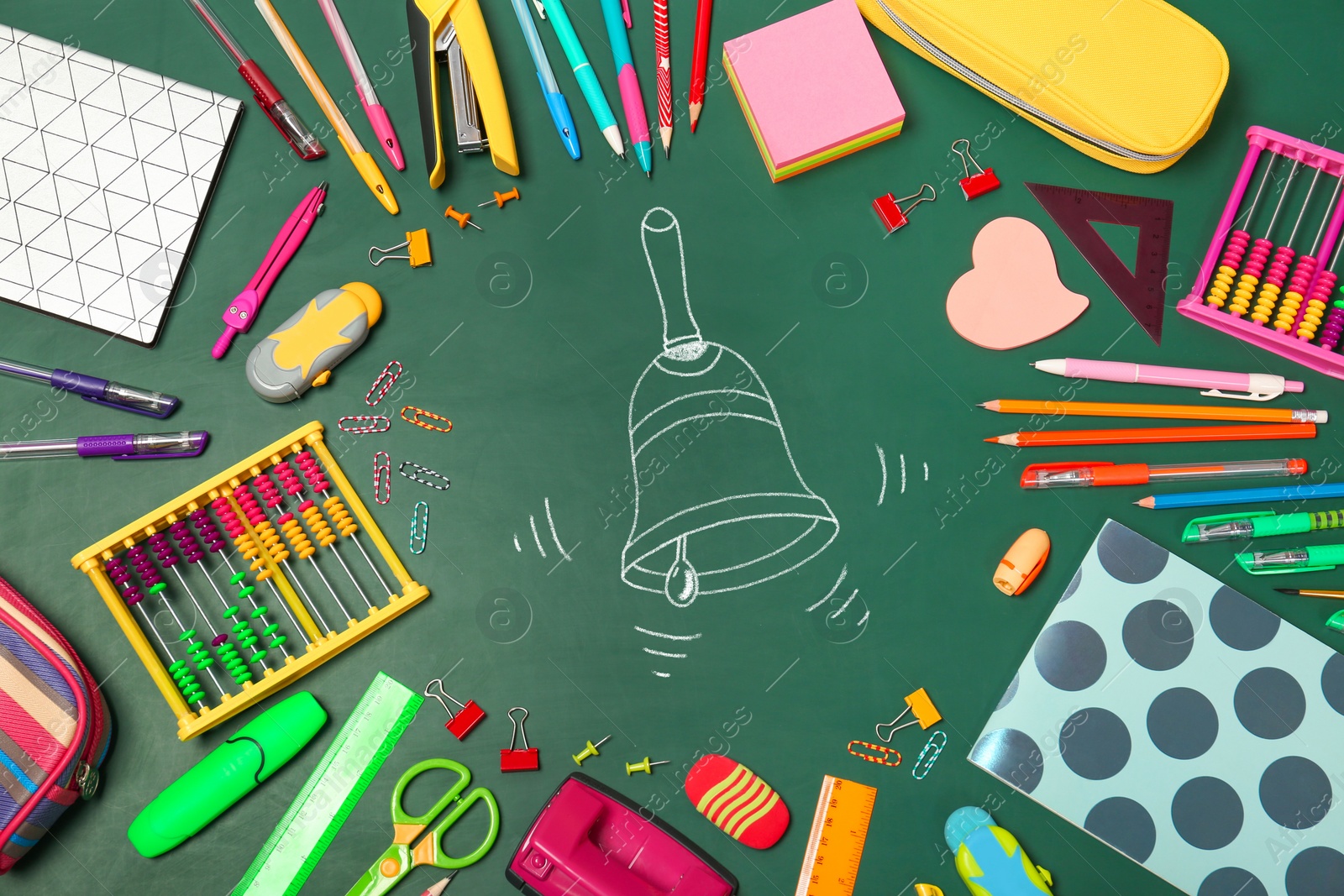 Image of Different stationery and drawn school bell on green chalkboard surface, flat lay