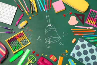 Different stationery and drawn school bell on green chalkboard surface, flat lay