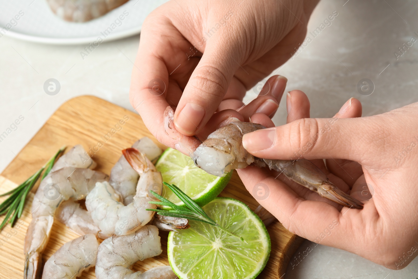 Photo of Woman peeling fresh shrimp at table, closeup