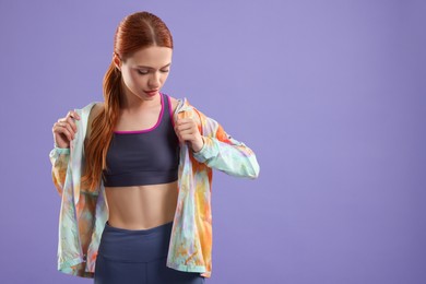 Photo of Young woman wearing sportswear on violet background, space for text