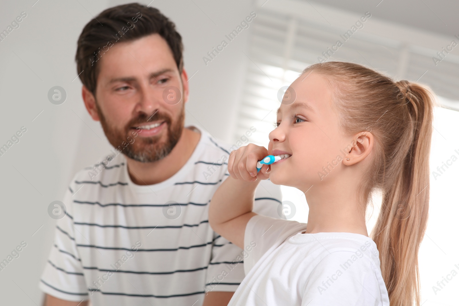 Photo of Father and his daughter brushing teeth together in bathroom