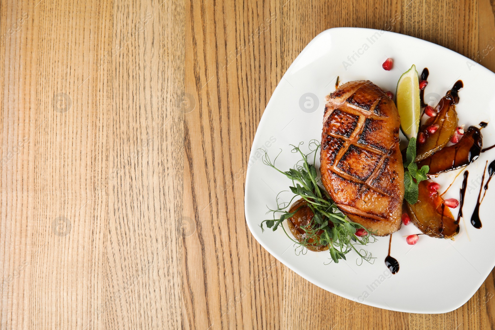 Photo of Delicious grilled duck breast served on wooden table, top view. Space for text