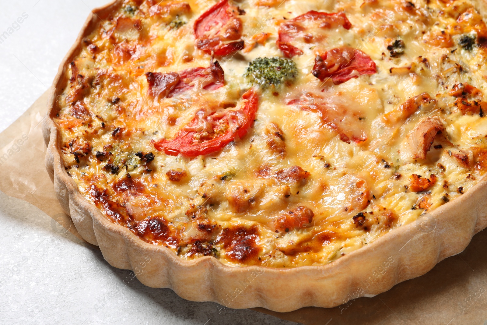 Photo of Tasty quiche with cheese and tomatoes on light grey table, closeup