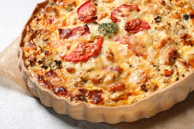 Tasty quiche with cheese and tomatoes on light grey table, closeup