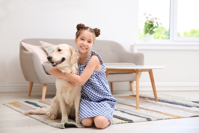 Photo of Cute little child with her pet on floor at home