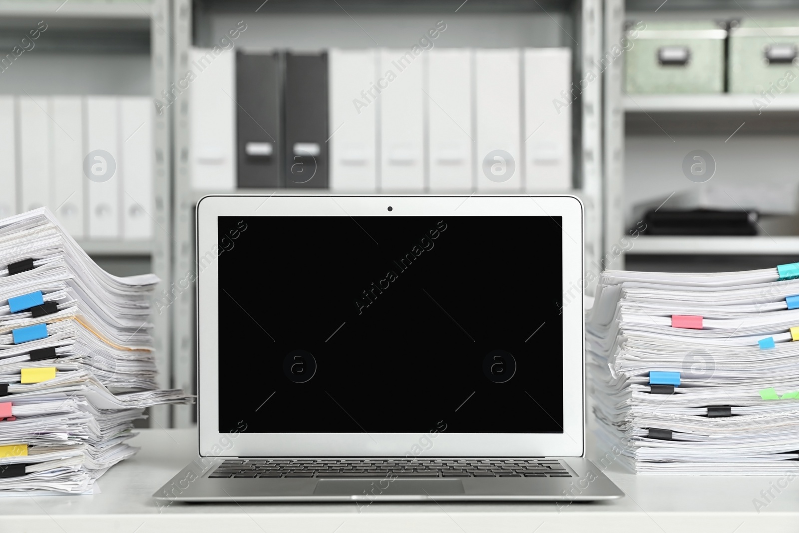 Photo of Laptop and documents on desk in office. Space for text