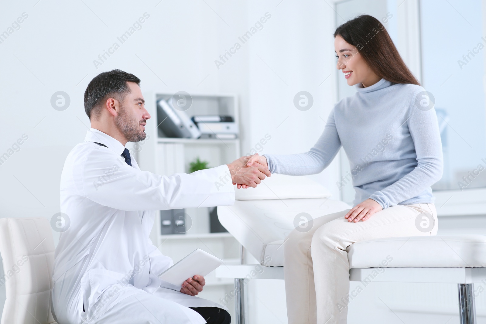 Photo of Happy doctor shaking hands with patient in hospital
