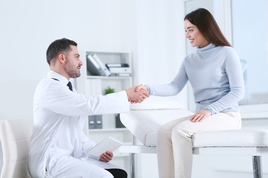 Photo of Happy doctor shaking hands with patient in hospital