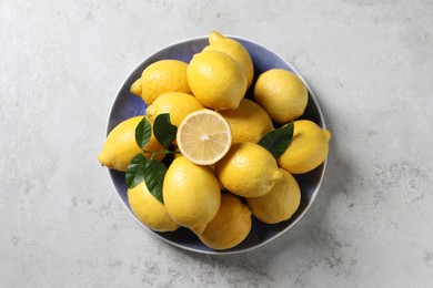 Photo of Fresh lemons and green leaves on light table, top view