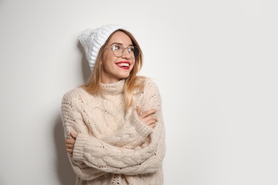 Beautiful young woman in warm sweater with hat on white background. Space for text