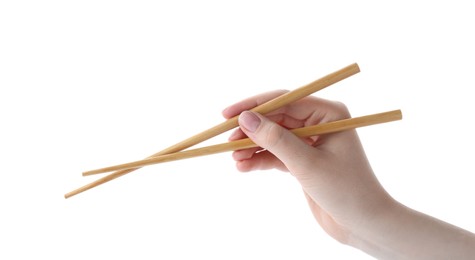 Woman holding pair of wooden chopsticks on white background, closeup