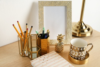 Modern workplace with notebook and golden decor on desk near wall. Stylish interior design