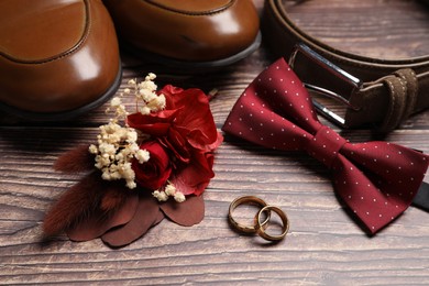 Photo of Wedding stuff. Composition with stylish boutonniere on wooden background, closeup