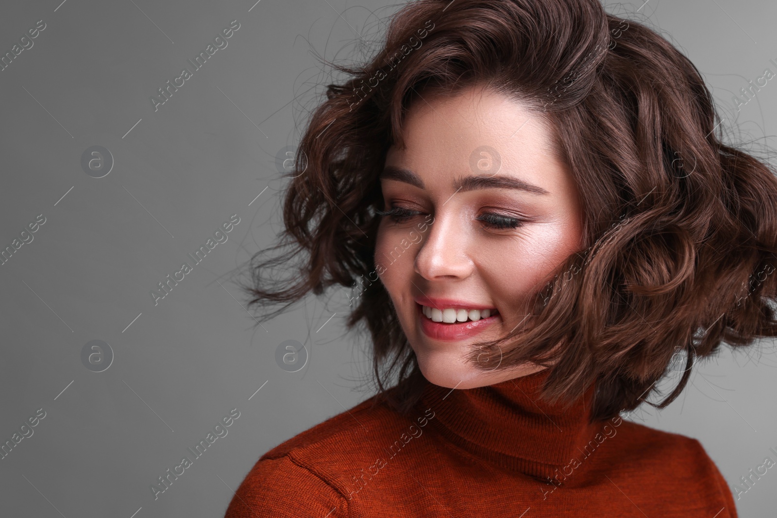 Photo of Portrait of beautiful young woman with wavy hairstyle on grey background. Space for text