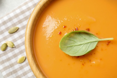 Photo of Tasty creamy pumpkin soup with basil in bowl on table, closeup