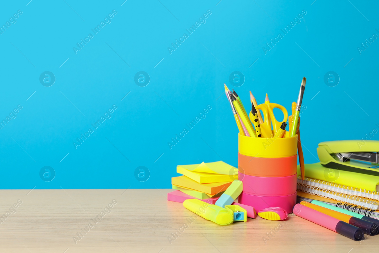 Photo of Composition with different school stationery on wooden table against light blue background, space for text. Back to school