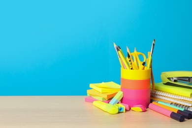 Photo of Composition with different school stationery on wooden table against light blue background, space for text. Back to school