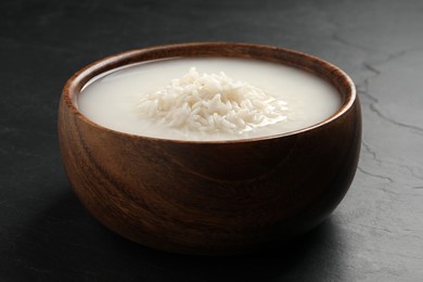 Photo of Rice soaked in water on black table, closeup