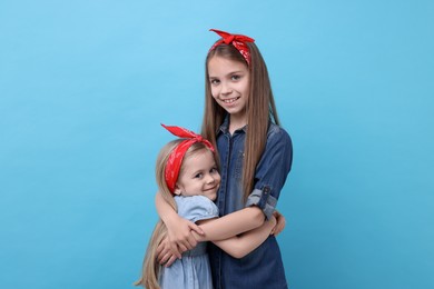 Photo of Cute little sisters on light blue background