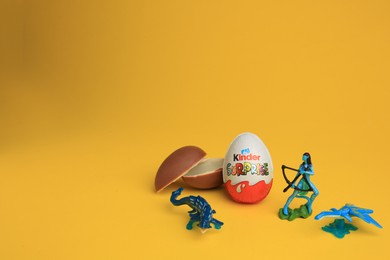 Photo of Sveti Vlas, Bulgaria - July 3, 2023: Kinder Surprise Eggs and toys on yellow background, space for text