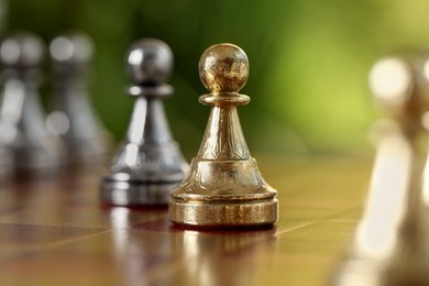 Photo of Golden pawn on chess board against blurred background, closeup