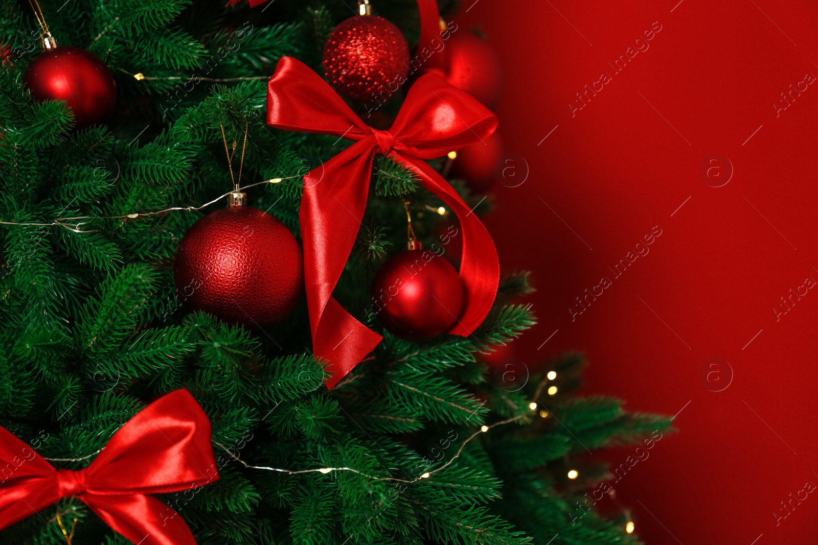 Photo of Decorated Christmas tree on red background, closeup