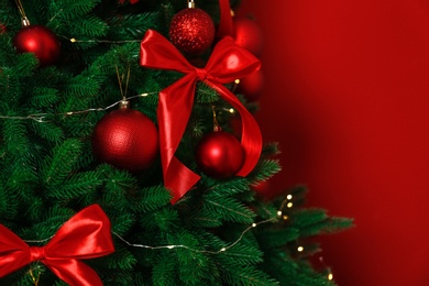 Photo of Decorated Christmas tree on red background, closeup