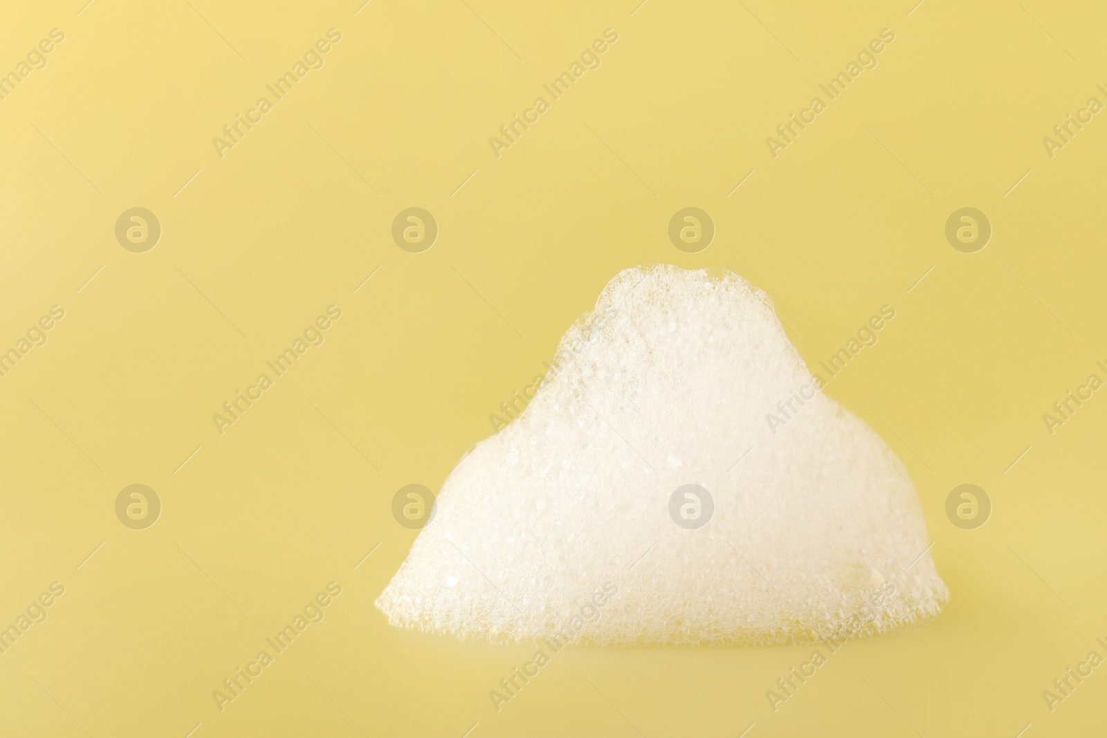 Photo of Drop of fluffy bath foam on pale orange background. Space for text