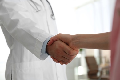 Photo of Doctor and patient shaking hands in clinic, closeup