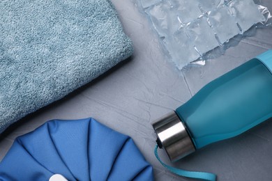 Photo of Bottle of water, cold compress, ice pack and towel on grey background, flat lay. Heat stroke treatment