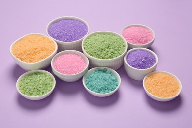 Different types of aromatic sea salt on purple background