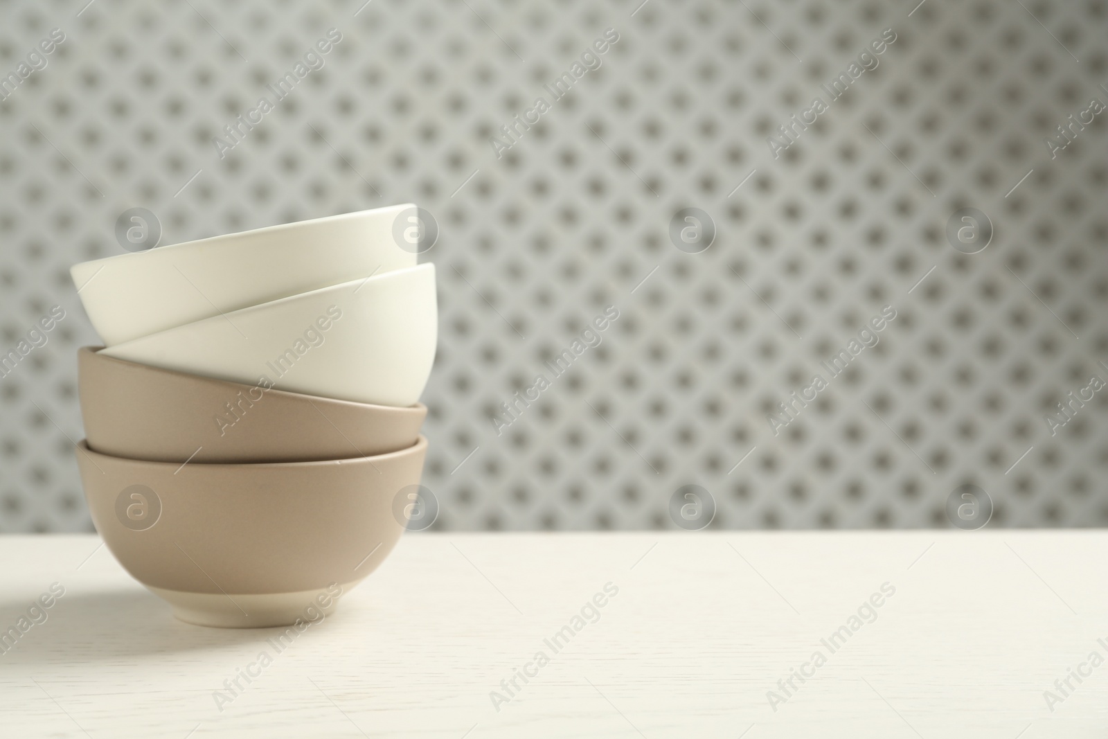 Photo of Stylish empty ceramic bowls on white wooden table, space for text. Cooking utensils