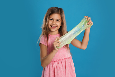 Photo of Little girl with slime on blue background