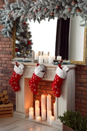 Photo of Decorative fireplace with Christmas stocking and gifts in stylish room interior