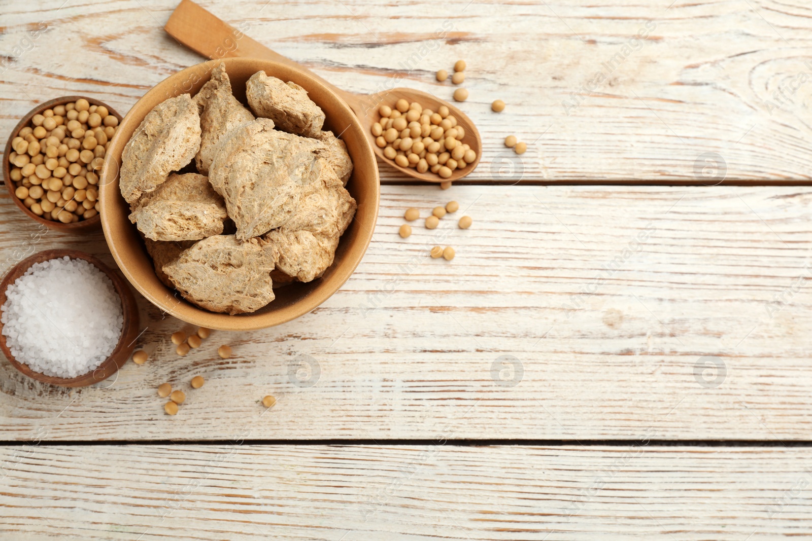 Photo of Flat lay composition with dehydrated soy meat on white wooden table. Space for text