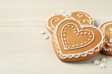 Photo of Tasty heart shaped gingerbread cookies on white wooden table, closeup. Space for text