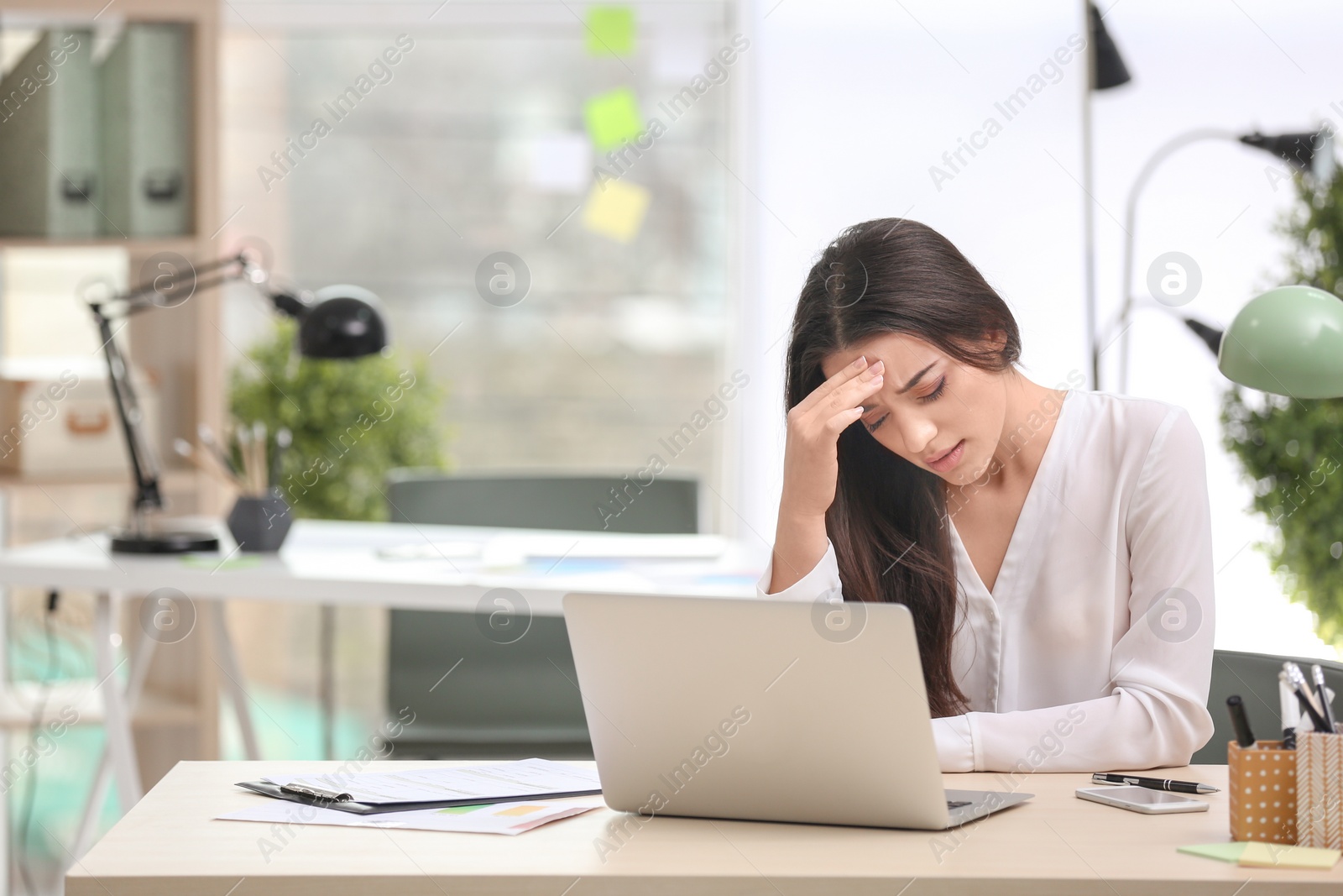 Photo of Young woman suffering from headache in office