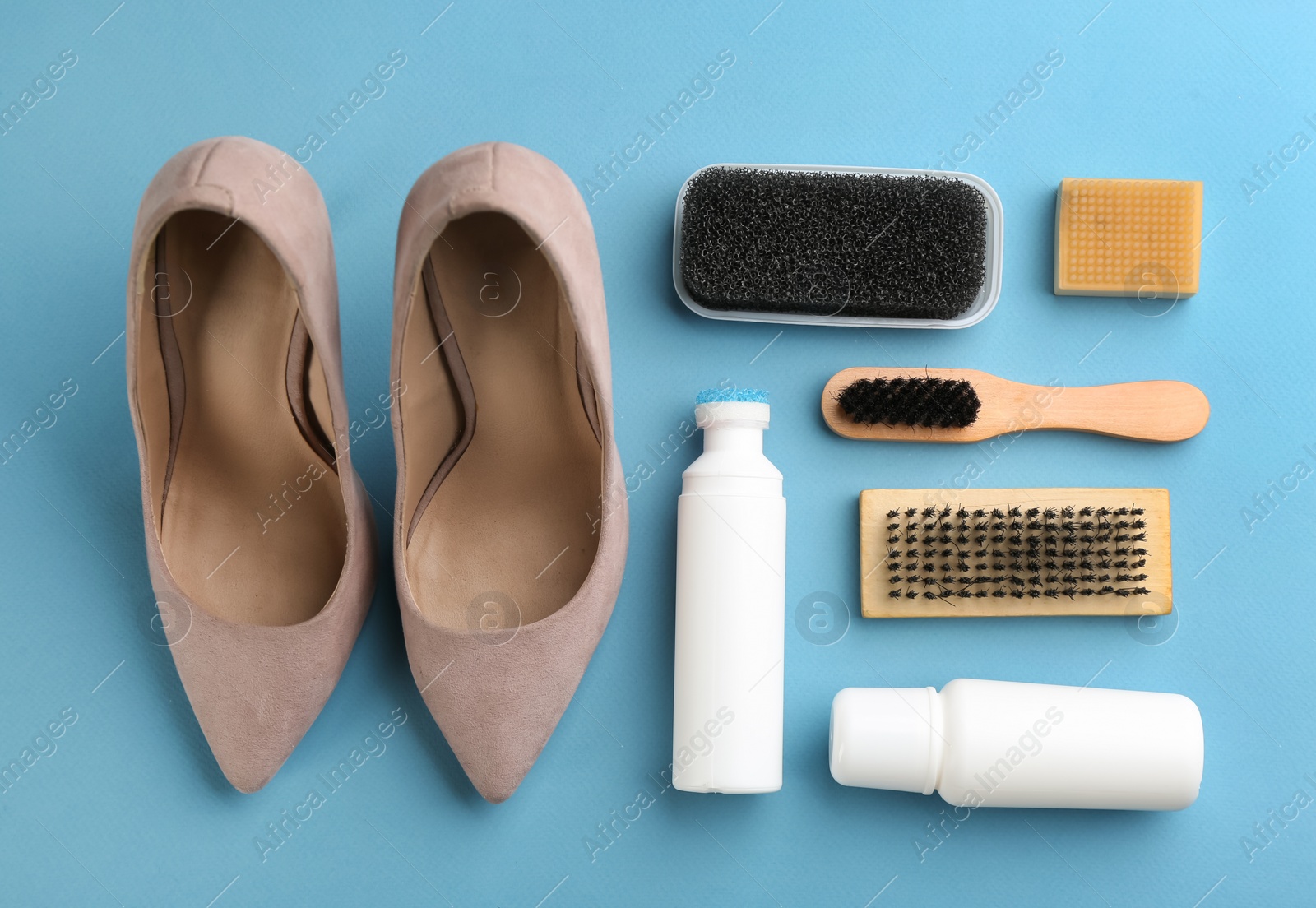 Photo of Stylish footwear with shoe care accessories on light blue background, flat lay