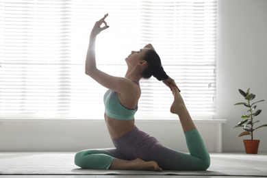 Photo of Woman practicing one legged king pigeon asana in yoga studio. Eka pada rajakapotasana pose