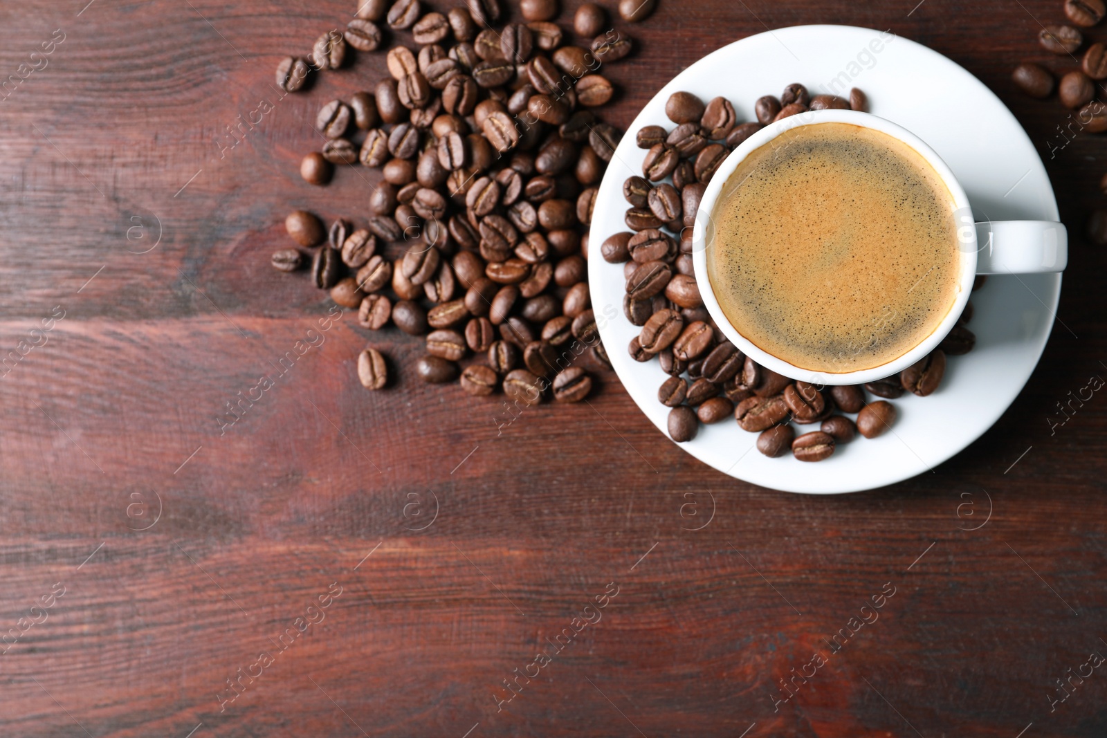 Photo of Cup of hot aromatic coffee and roasted beans on wooden table, flat lay. Space for text