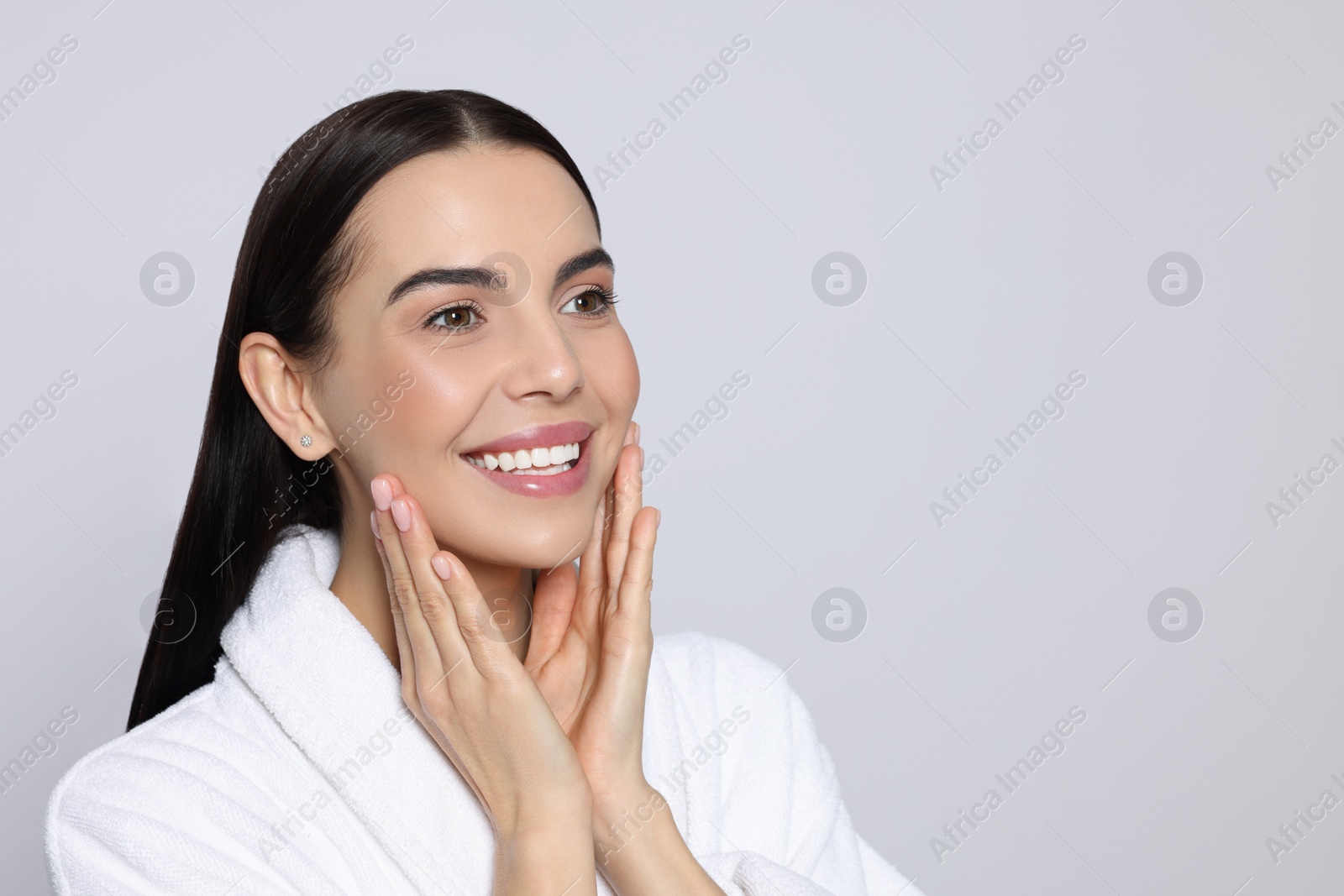 Photo of Portrait of attractive young woman in bathrobe on light grey background, space for text. Spa treatment