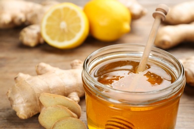 Photo of Ginger, honey and lemon on wooden table, closeup. Natural cold remedies