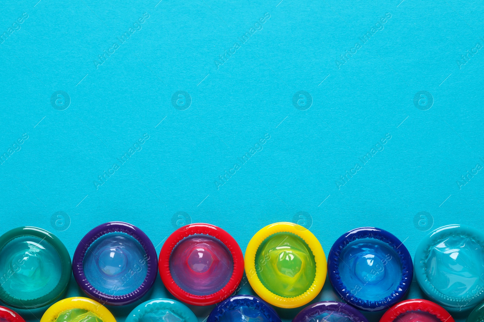 Photo of Colorful condoms on light blue background, flat lay. Space for text
